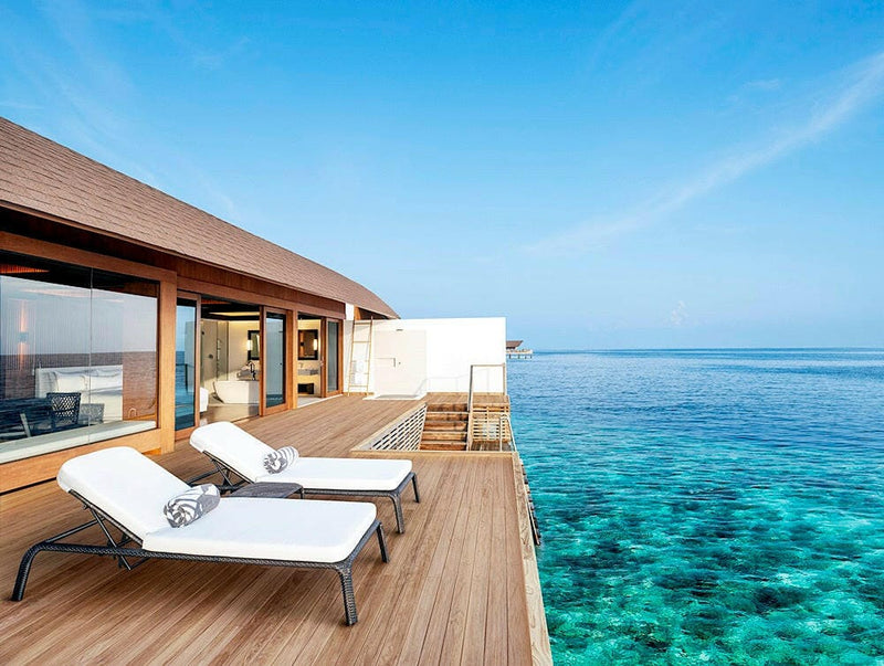 A villa deck at The Westin Maldives Miriandhoo, two white loungers facing open turquoise water.