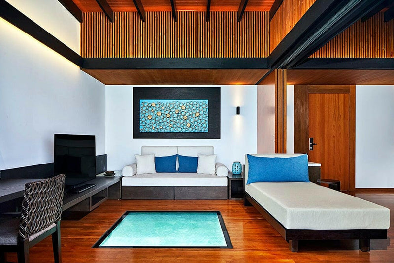 A villa living room at The Westin Maldives Miriandhoo, blue cushioned sofa beside a lit floor panel.