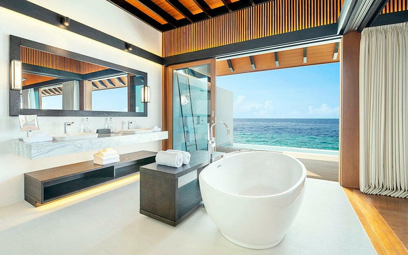A villa bathroom at The Westin Maldives Miriandhoo, round tub and twin basins open to the sea.