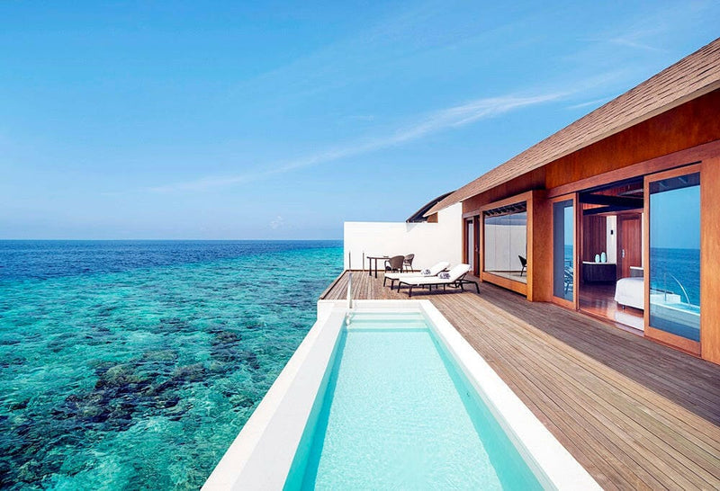 An overwater villa pool at The Westin Maldives Miriandhoo, decking running out over dark coral.