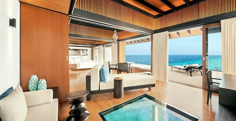 A villa lounge at The Westin Maldives Miriandhoo, teal vases and a glass panel down into the lagoon.