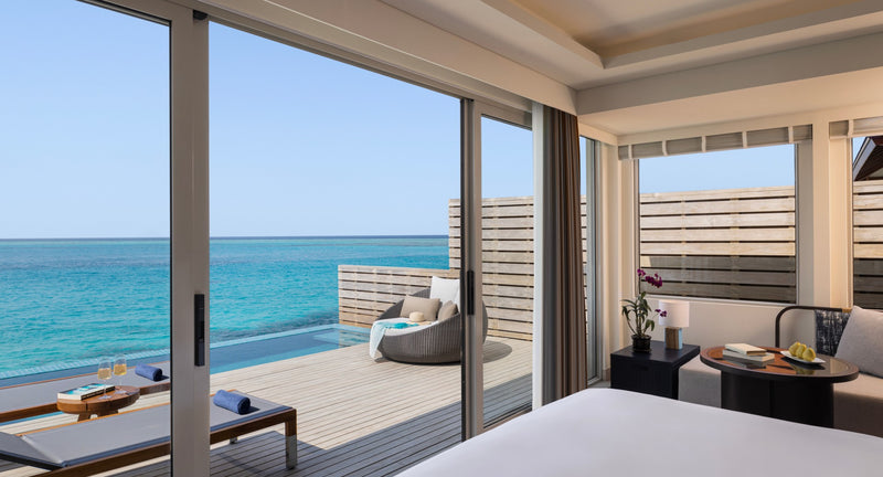 An Overwater Pool Villa bedroom at Avani+ Fares Maldives, opening to a sea-view deck with a private pool.