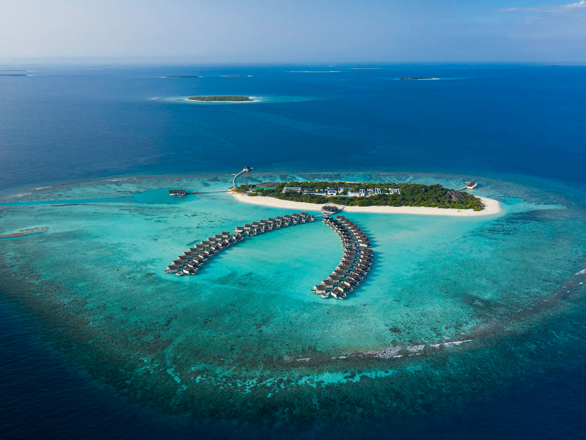 An aerial view of Kuredhivaru Resort & Spa Maldives and its overwater villas.