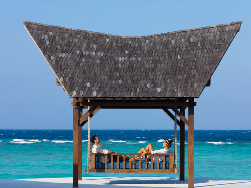 A couple on a swing above the lagoon at Kuredhivaru Resort & Spa Maldives.
