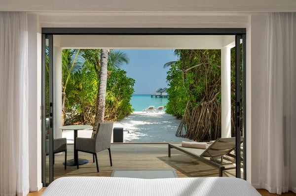 A bedroom in a Two Bedroom Beach House at Niva Kuramathi Maldives, opening onto the outdoors.