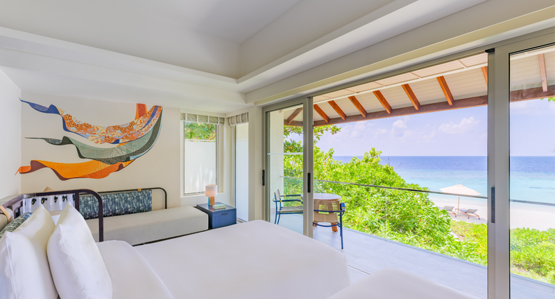 A Premium Ocean View Room at Avani+ Fares Maldives, with a day bed and a balcony view over the trees to the sea.
