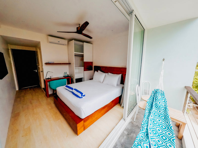 Deluxe Room at Bliss Dhigurah with a queen bed and a hammock on the balcony