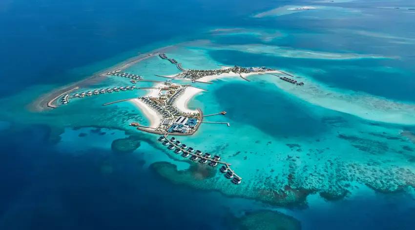 Centara Grand Lagoon Maldives from the air, the island and its overwater villa jetties.