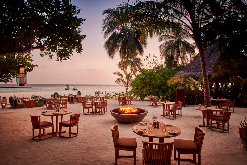 Constance Halaveli, North Ari Atoll: Meeru restaurant tables and fire pits set out on the sand at dusk