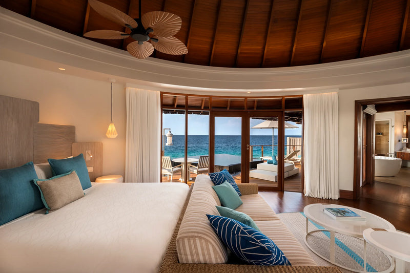 Constance Halaveli, North Ari Atoll: circular Water Villa bedroom under a timber ceiling, glass doors looking out to sea