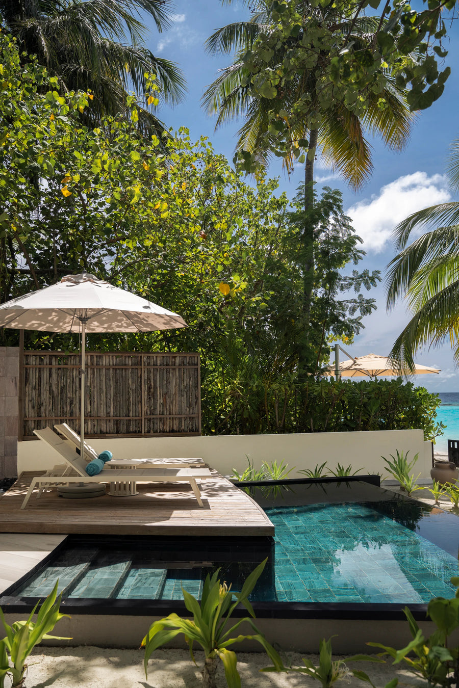 Constance Halaveli, North Ari Atoll: Beach Villa private pool with a lounger and umbrella, garden wall and a glimpse of the sea