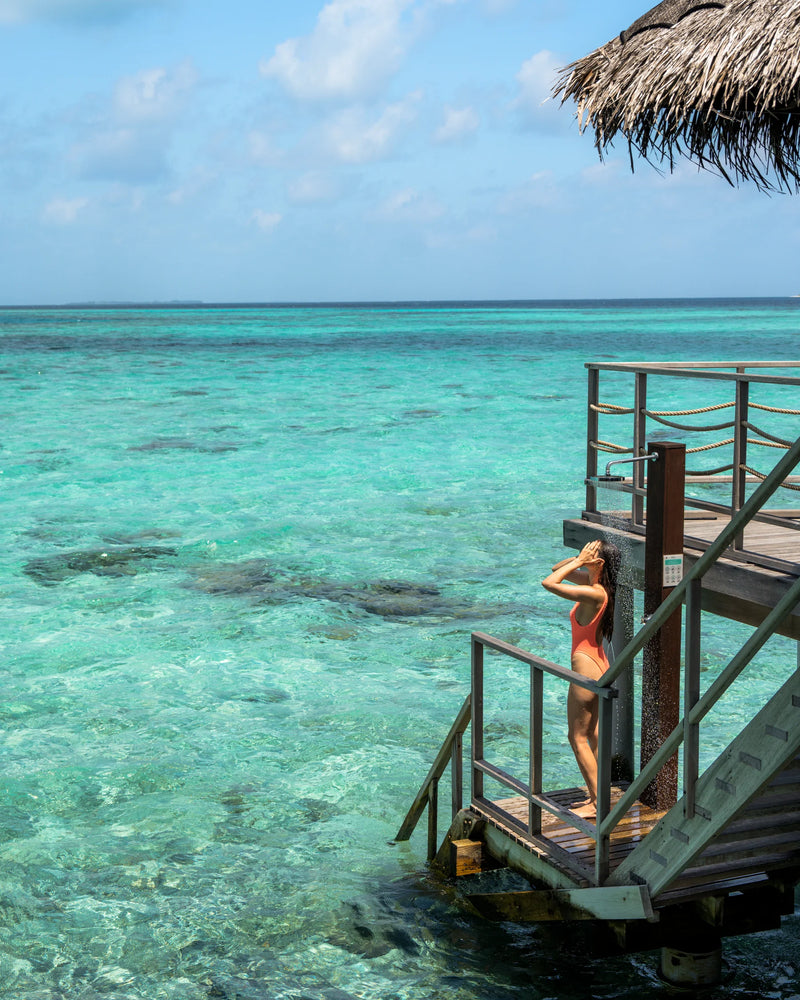 Constance Moofushi, South Ari Atoll: a guest on the steps from a Water Villa deck down to the reef
