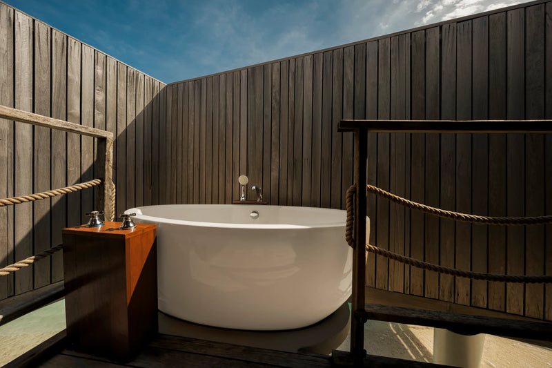 Constance Moofushi, South Ari Atoll: freestanding bathtub in the open-air bathroom of a Senior Sand Villa, behind a timber screen