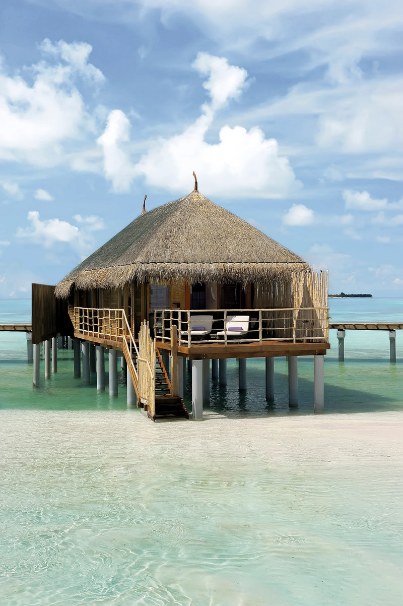 Constance Moofushi, South Ari Atoll: a thatched Senior Water Villa on stilts over the shallow lagoon, its deck and steps facing the sea