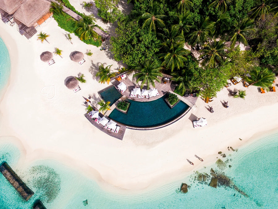 Constance Moofushi, South Ari Atoll: the main pool from above, sun loungers and palms beside the beach