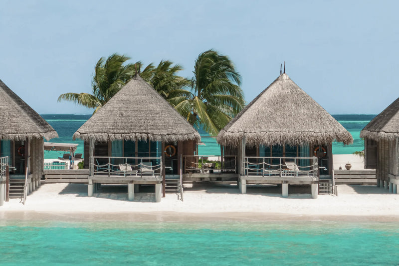 Constance Moofushi, South Ari Atoll: two thatched Sand Villas on stilts at the edge of the beach, steps leading down to the lagoon