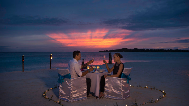 A couple dining at the water's edge at Cocoon Maldives.