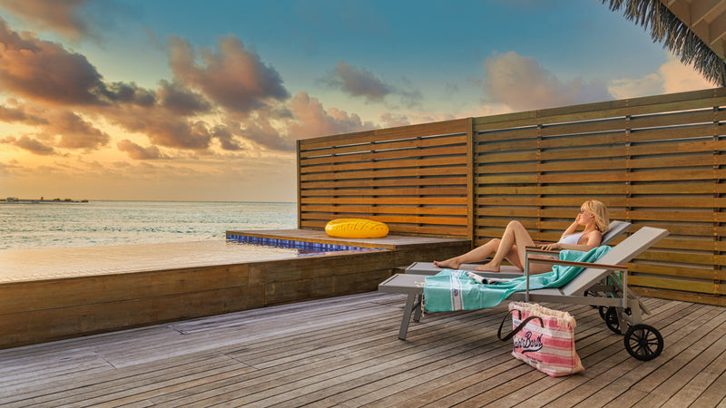 A guest on a deck at sunset at Cocoon Maldives.