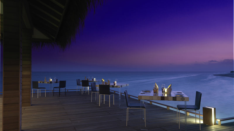 A restaurant deck at dusk at Cocoon Maldives.
