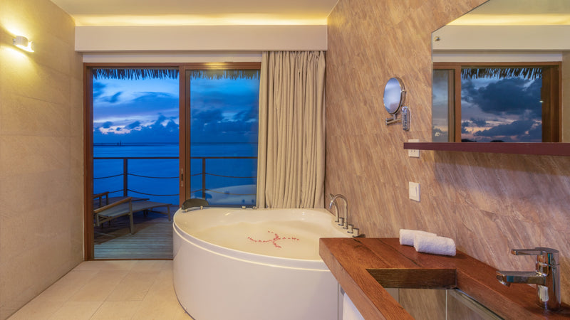 A bathroom with a tub and a sea view at Cocoon Maldives.