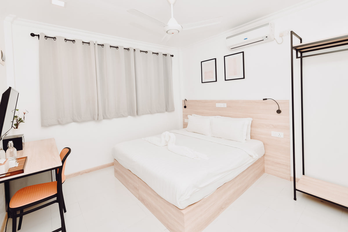 White double room at Nala Island Village with a double bed, desk, clothes rail and air-conditioning