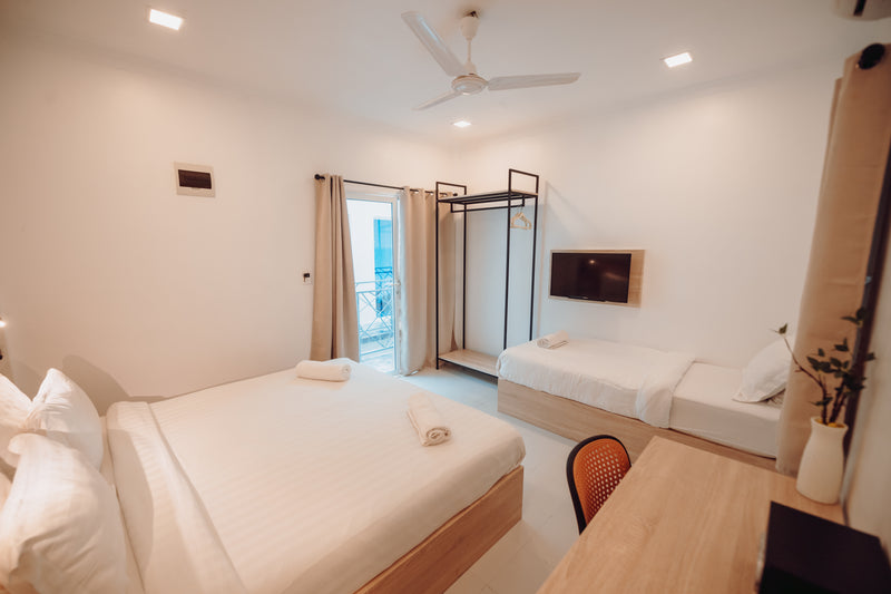 Triple room with a double bed and a single bed, wall-mounted TV and clothes rail at Nala Island Village