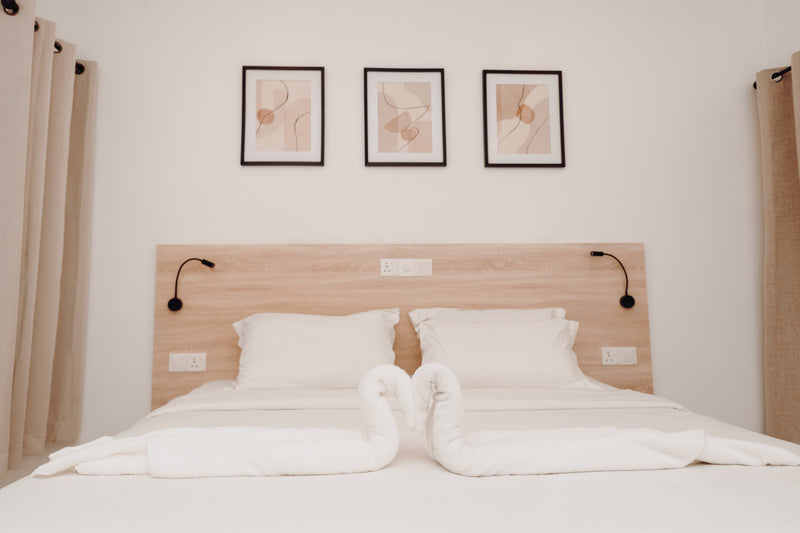 Bed folded with towel swans under three framed prints at Nala Island Village
