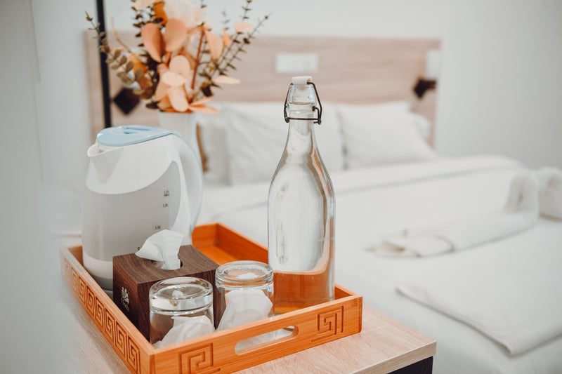 Tray with a kettle, glasses and a water bottle beside the bed at Nala Island Village