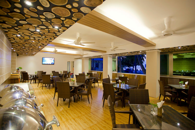 Restaurant at Kaani Beach Hotel with tables set beside large windows
