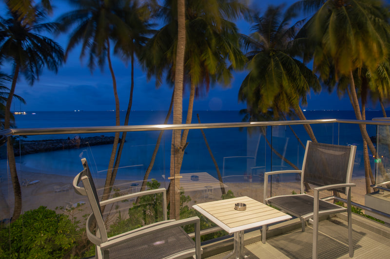 Balcony with chairs overlooking the sea through palm trees at dusk, Kaani Grand Seaview