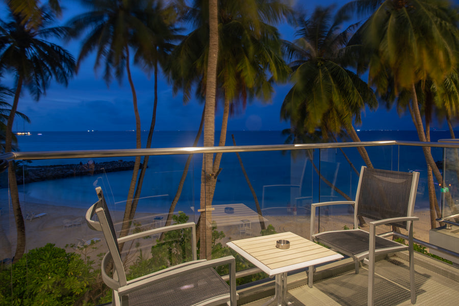 Balcony with chairs overlooking the sea through palm trees at dusk, Kaani Grand Seaview