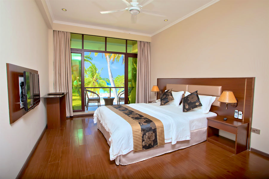 Double room at Kaani Beach Hotel with a balcony door open to the palms