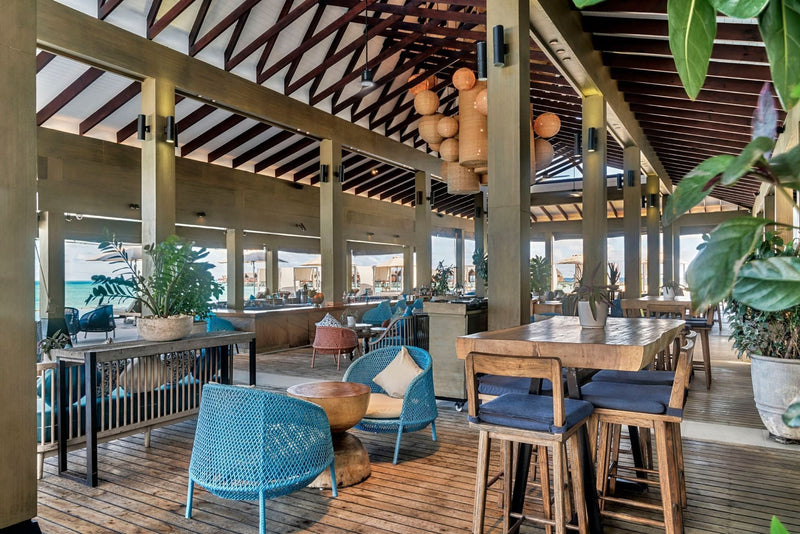 Breeze at Grand Park Kodhipparu, an indoor and outdoor dining area with blue chairs and timber tables