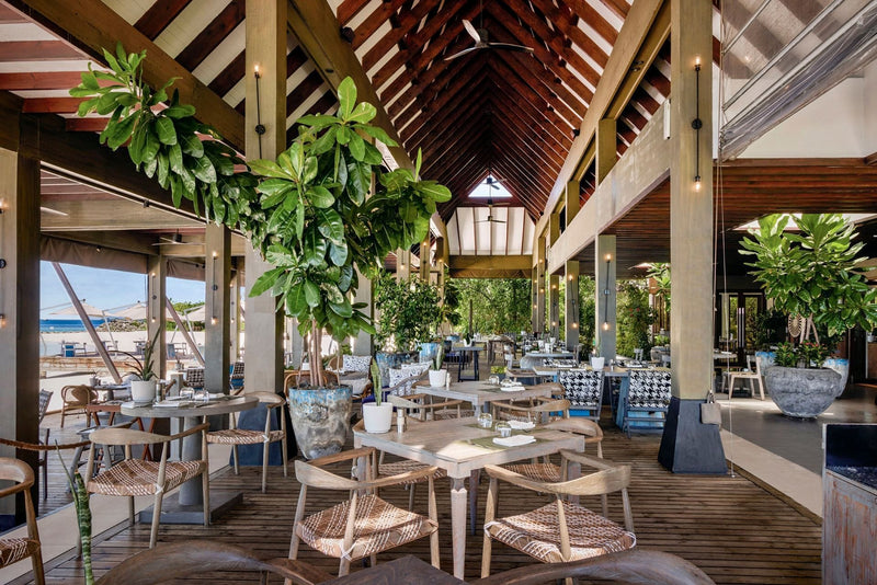The Edge at Grand Park Kodhipparu, an outdoor dining area with timber tables among planting