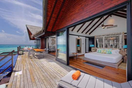 The main bedroom of the Grand Residence at Grand Park Kodhipparu, doors open onto its deck