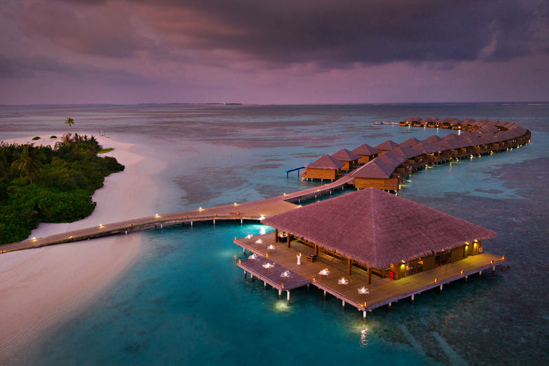 An overwater building at Cocoon Maldives at dusk.