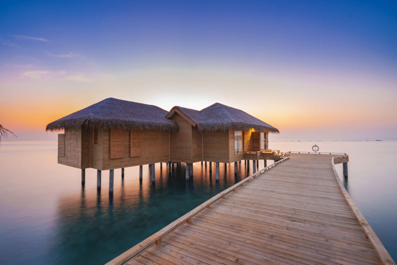 An overwater villa at You & Me Maldives at dusk.