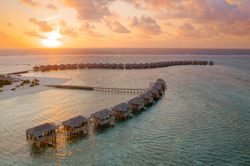 The overwater villas at You & Me Maldives at sunset.