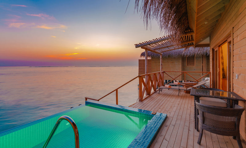 The deck and pool of an overwater villa at sunset at You & Me Maldives.