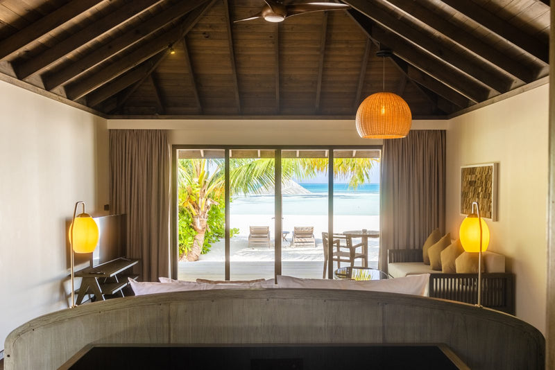Jawakara Islands Maldives, Lhaviyani Atoll: a Mabin beach villa bedroom opening through glass doors onto the beach