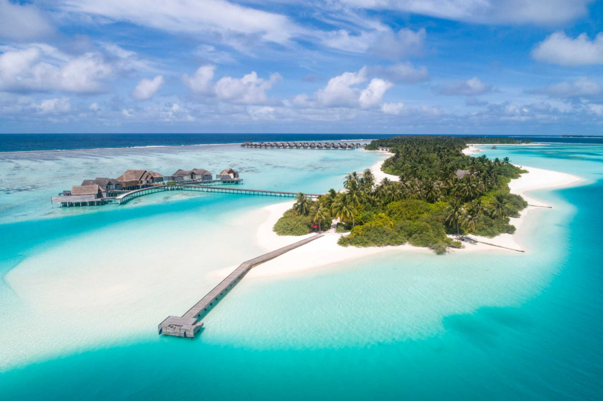 Aerial view of Niyama Private Islands in Dhaalu Atoll, with overwater villas and a jetty reaching across the turquoise lagoon between its two islands