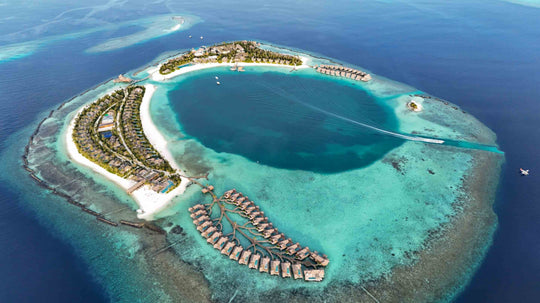 ananea Madivaru Maldives from high above, the island and its overwater villas ringed by reef