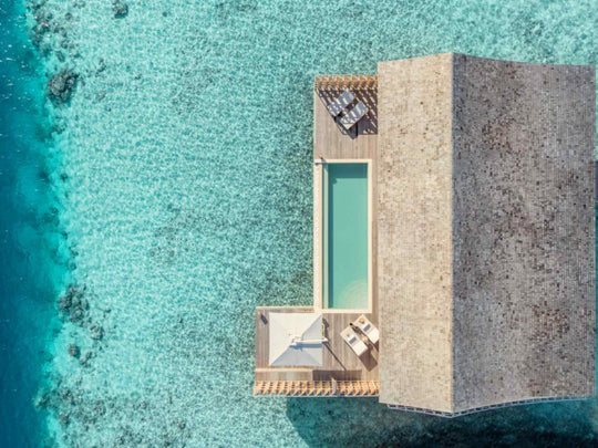 Kudadoo Maldives Private Island, Lhaviyani Atoll — aerial view looking straight down on an overwater residence, its private pool and sun deck set against the turquoise reef edge