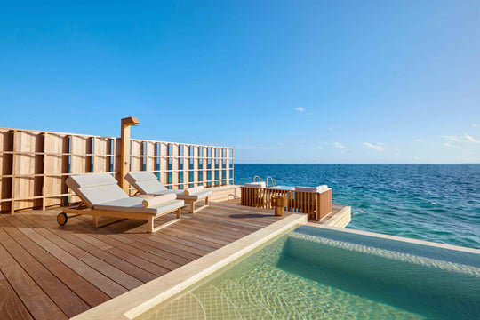 Kudadoo Maldives Private Island, Lhaviyani Atoll — sun deck with two loungers and an outdoor shower beside the infinity pool, open ocean ahead