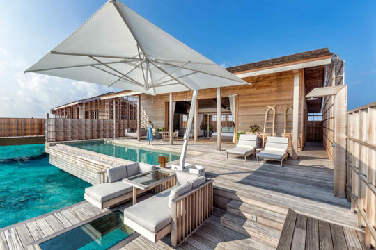 Kudadoo Maldives Private Island, Lhaviyani Atoll — exterior of a residence showing the timber deck, loungers, parasol and private pool set out over the lagoon