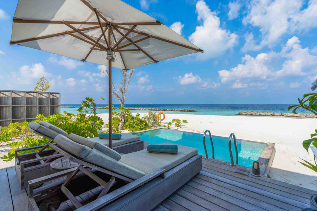 Kagi Maldives Resort &amp; Spa, North Malé Atoll — beach villa deck with a parasol, twin sun loungers and a private pool looking out to the sand and lagoon