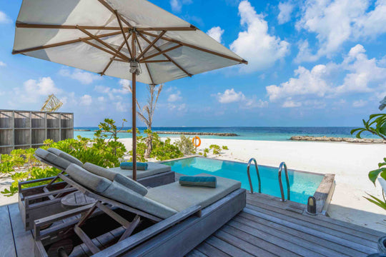 Kagi Maldives Resort &amp; Spa, North Malé Atoll — beach villa deck with a parasol, twin sun loungers and a private pool looking out to the sand and lagoon