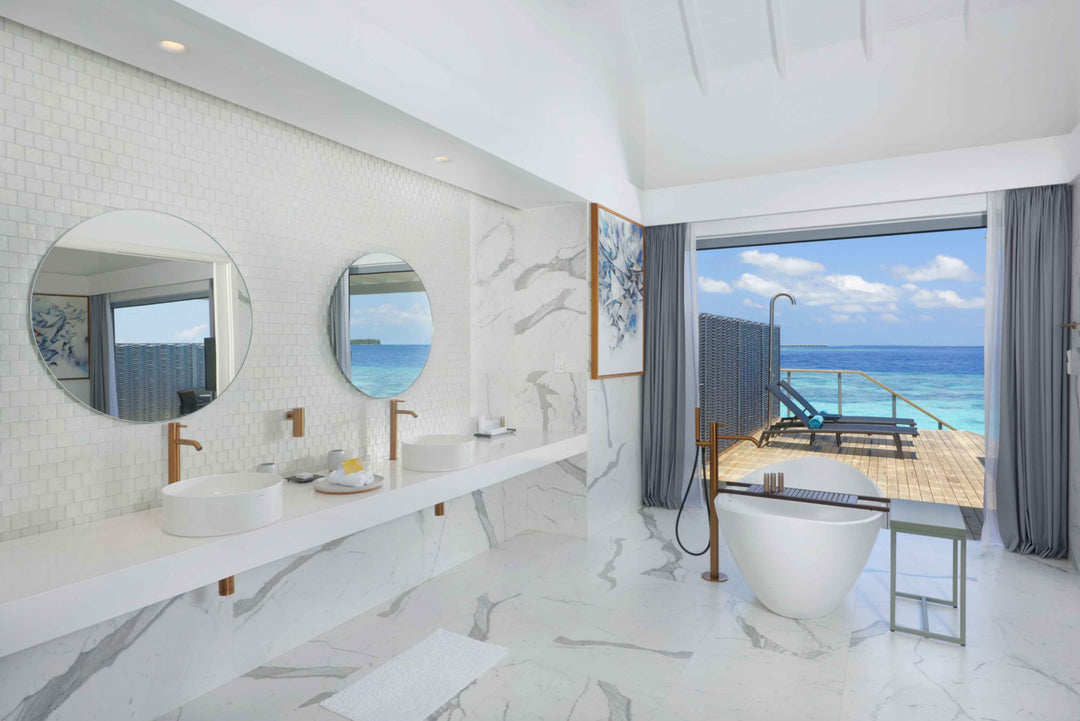 Twin round mirrors above a marble vanity, freestanding bath beside the door to the deck