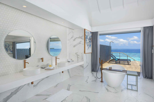 Twin round mirrors above a marble vanity, freestanding bath beside the door to the deck