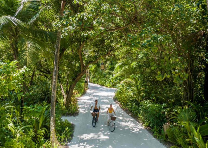 Guests cycling along a shaded path through the greenery at Niyama Private Islands